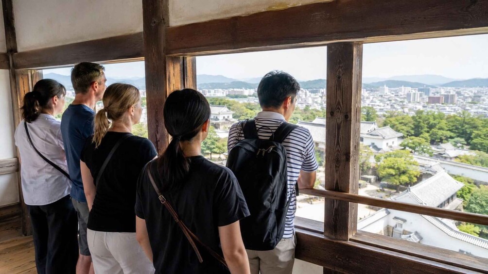A group of people standing by a window overlooking a cityscape with traditional buildings and greenery. 4