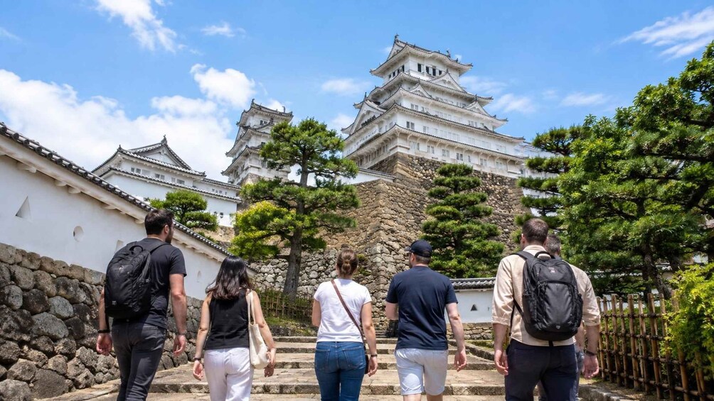 A group of people walking towards a traditional Japanese castle with multiple tiers and white walls. 3