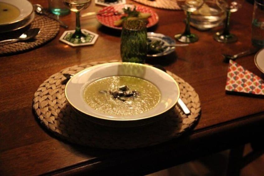 A table set with a bowl of soup, a glass of water, and a wine glass. 4