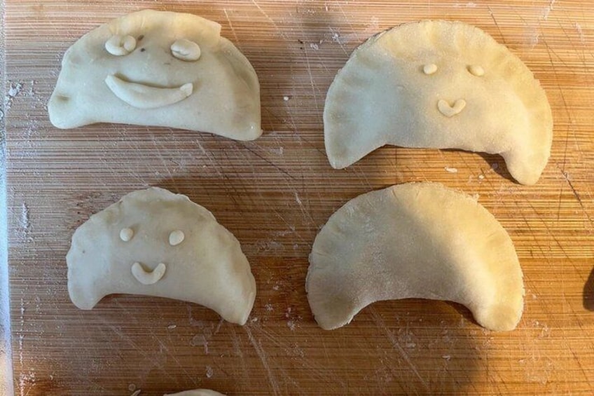 Four dumplings with smiley faces on a wooden surface. 3