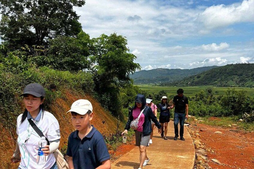 A group of people walking on a dirt path surrounded by greenery and hills. 5
