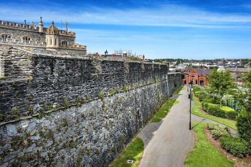 A stone wall, a pathway, and a building with a dome. 5