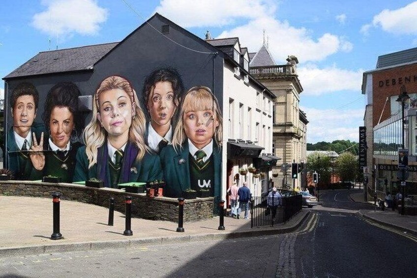 A street with a mural of characters, a building with a sign, and a clear sky. 2