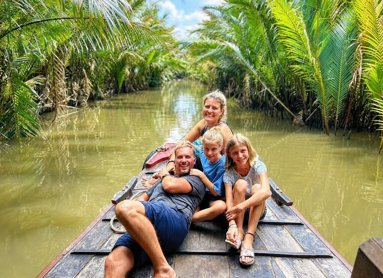 A family on a wooden boat in a river surrounded by lush greenery. 5