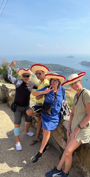 Four people sitting on a stone ledge with a coastal landscape in the background. 2