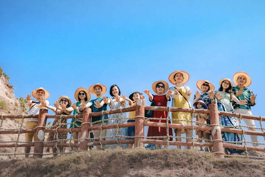 A group of people standing on a wooden bridge with a clear blue sky in the background. 2