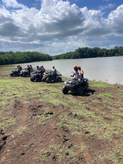 A group of people on ATVs near a lake with a cloudy sky. 3