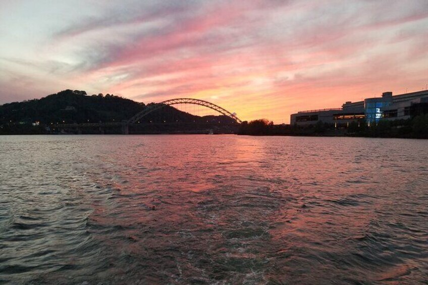 A sunset over a river with a bridge and buildings in the background. 4