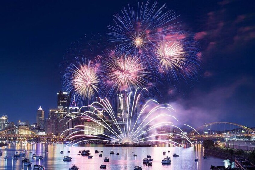 A city skyline with fireworks over a body of water reflecting city lights. 5