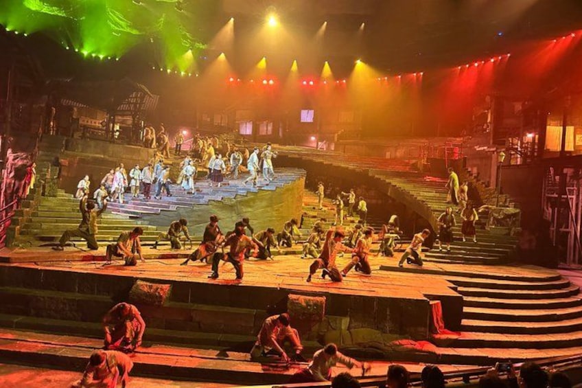 A stage with performers in traditional costumes, a staircase, and a crowd watching. 4