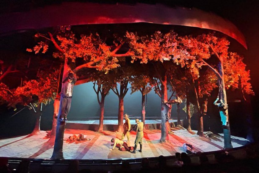 A stage with a backdrop of trees and a group of people. 5