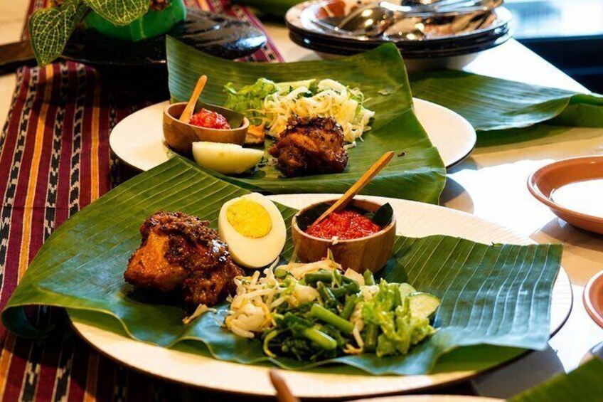 A meal served on banana leaves with grilled meat, rice, vegetables, and a boiled egg. 4