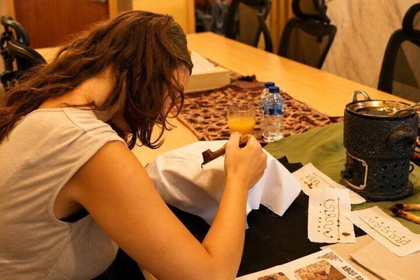 A person sitting at a table with a notebook, a pen, and a thermos. 2