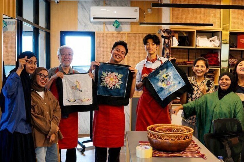 A group of people holding framed artworks in a workshop setting. 5