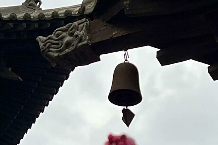 A traditional bell hanging from a roof with ornate carvings. 3
