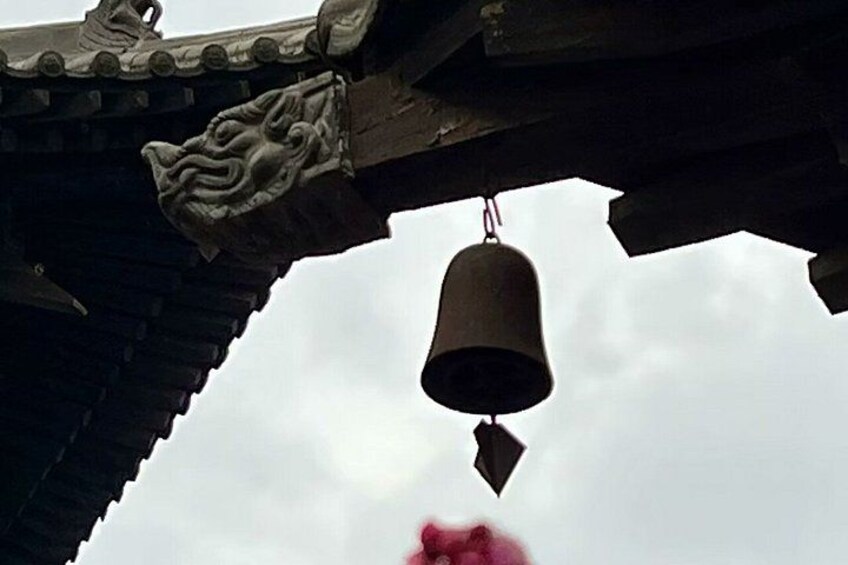 A traditional bell hanging from a roof with ornate carvings. 3