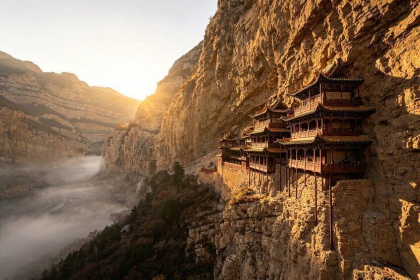 A traditional multi-tiered building perched on a cliffside, overlooking a valley with a misty river below. 1