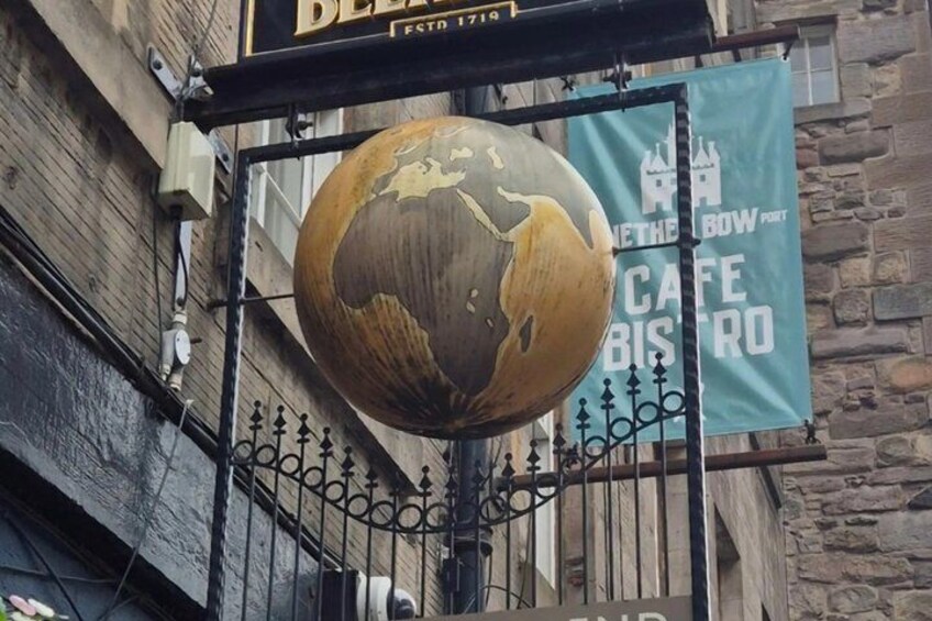 A globe hanging from a metal frame, a stone building, and banners with text. 1