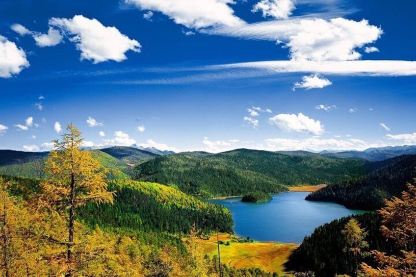 A lake surrounded by forested hills under a clear sky. 2