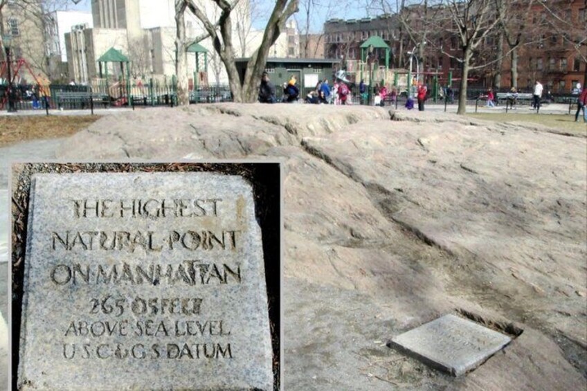 A stone plaque with text, a park with people, and a playground in the background. 5