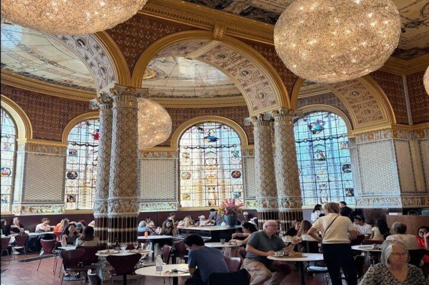 A grand dining hall with ornate columns, large windows, and hanging chandeliers. 4