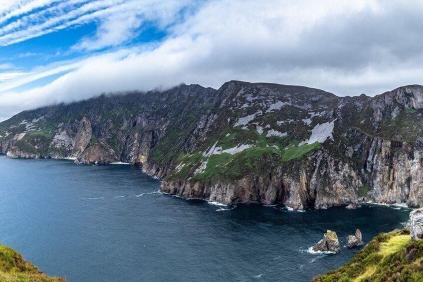 A rugged coastline with steep cliffs, a narrow sea passage, and a clear sky. 4