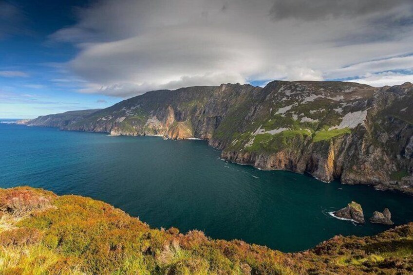 A coastal landscape with cliffs, a body of water, and vegetation. 3