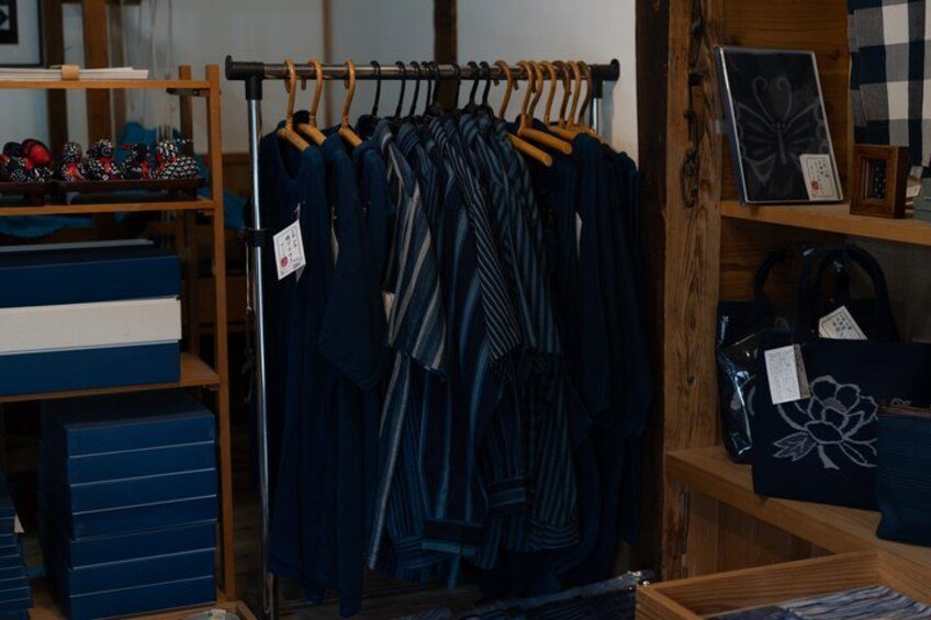 A clothing store with racks of clothes, shelves with bags, and boxes. 4