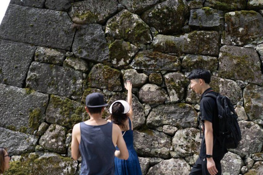 People climbing a moss-covered stone wall. 3