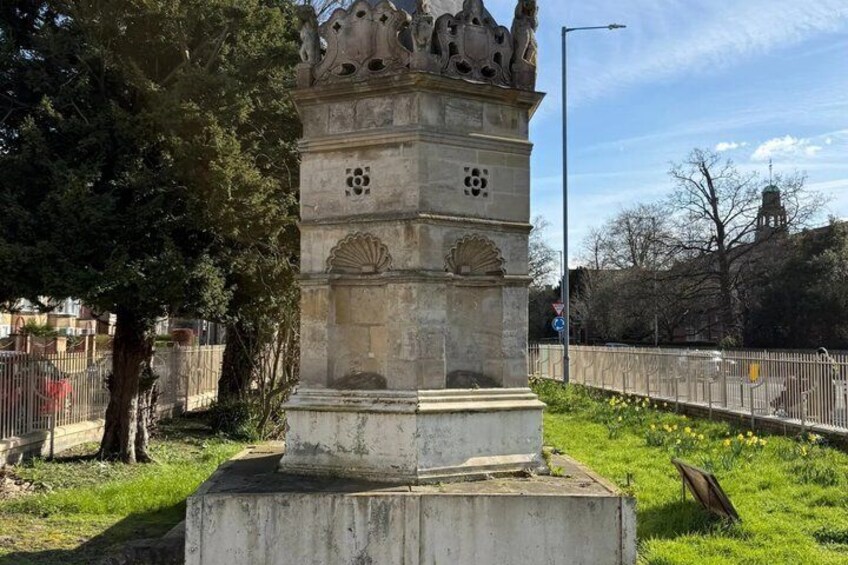 A stone monument with intricate carvings, surrounded by grass and trees. 2