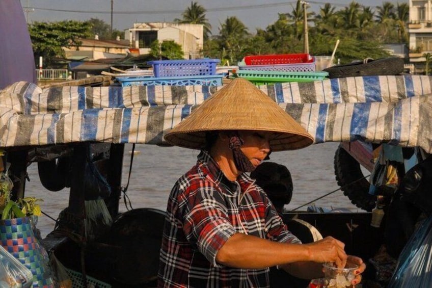 A person wearing a conical hat, working on a boat with a striped awning. 4