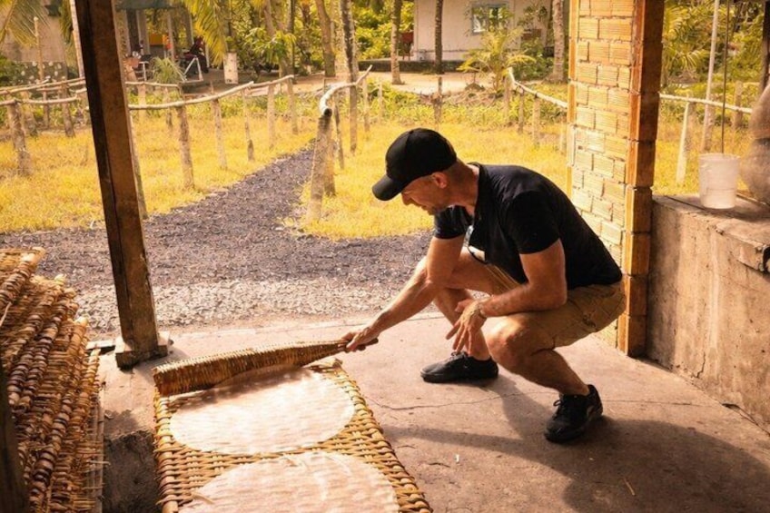 A person working on a woven mat outdoors. 3