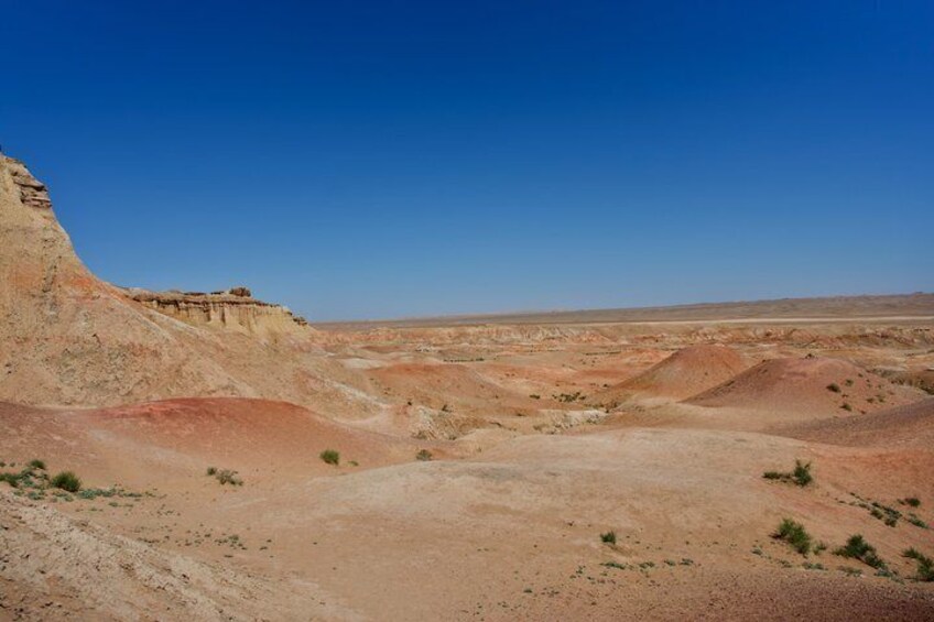 A desert landscape with a prominent cliff and sparse vegetation. 3