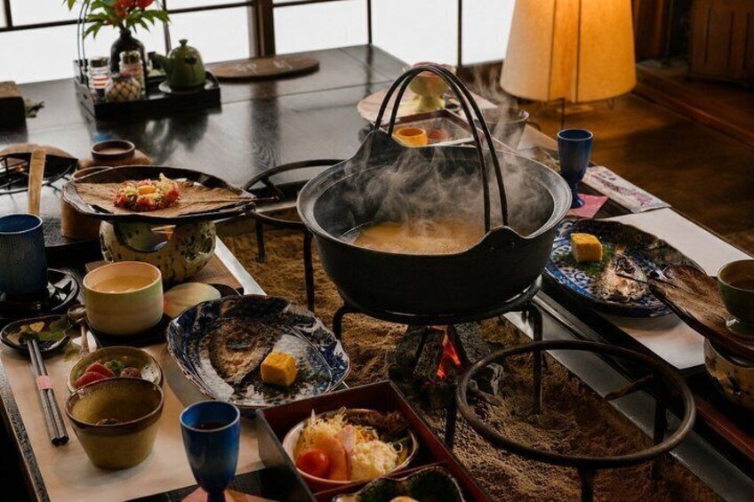 A traditional Japanese meal setup with a hot pot, various dishes, and utensils on a wooden table. 1