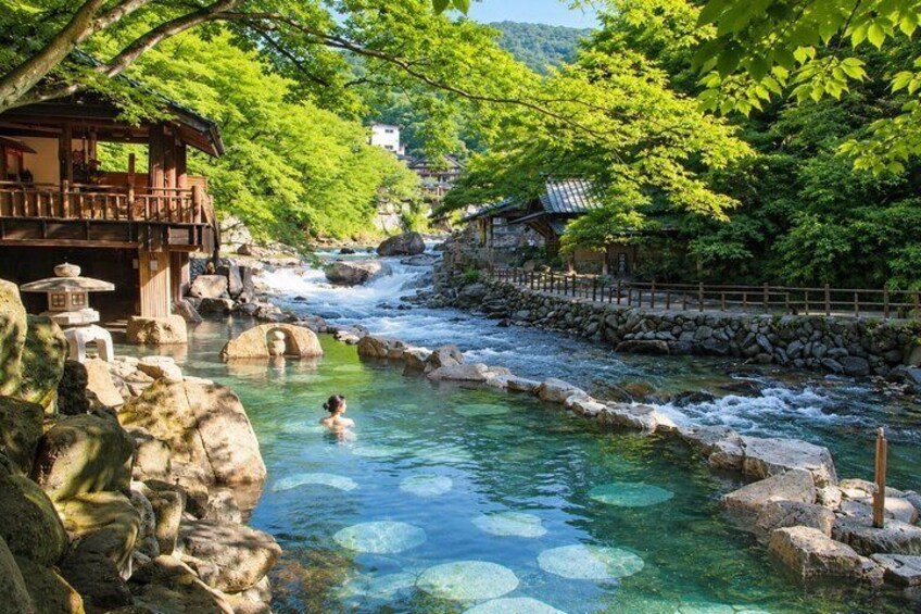 A clear river with rocks, a wooden structure, and lush greenery. 2
