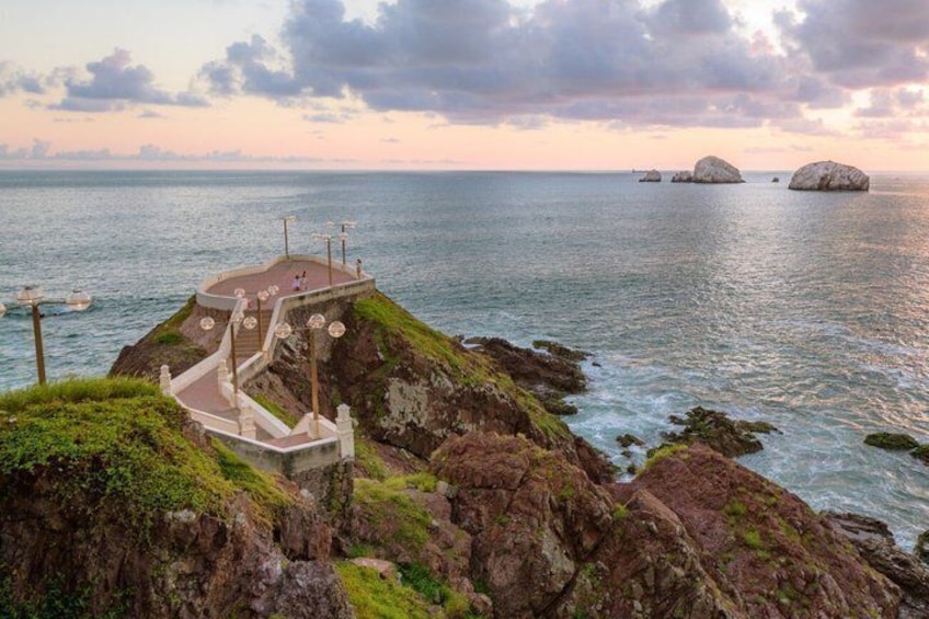 A coastal viewpoint with a staircase leading to a platform overlooking the sea, surrounded by rocky terrain. 2