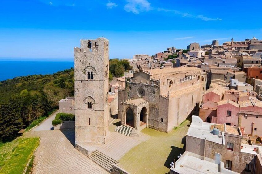 A historic town with a prominent tower, cobblestone streets, and a coastal backdrop. 4