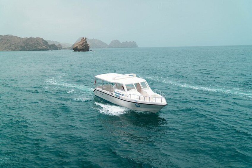 A white boat on calm water with a rocky coastline in the background. 3