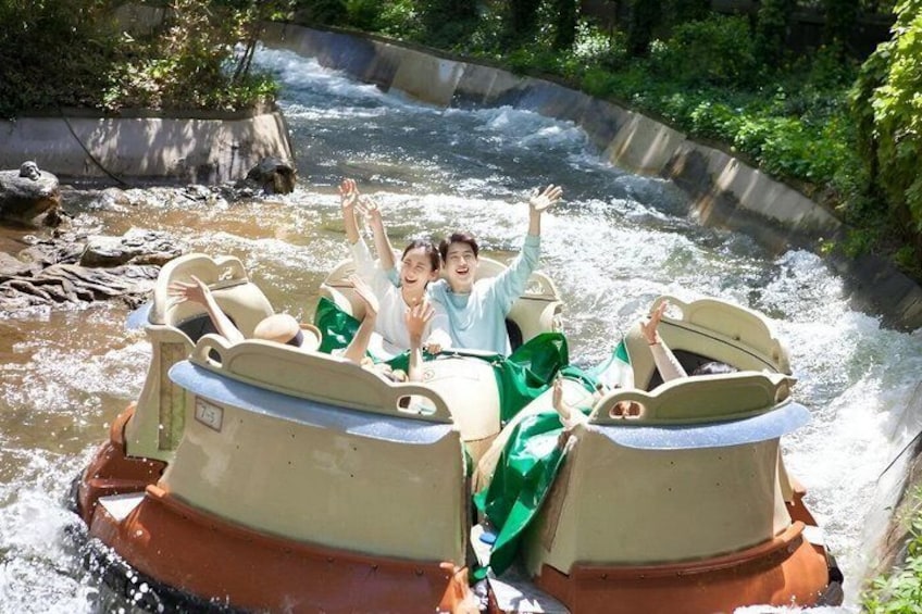 Two people in a boat with raised arms, surrounded by water and greenery. 3