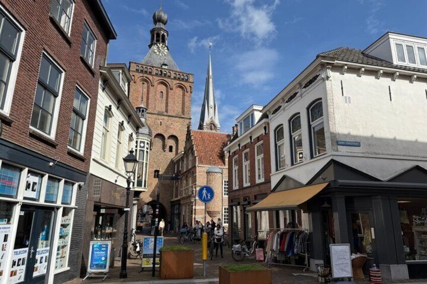 A historic town square with a church spire, traditional buildings, and a pedestrian crossing. 5