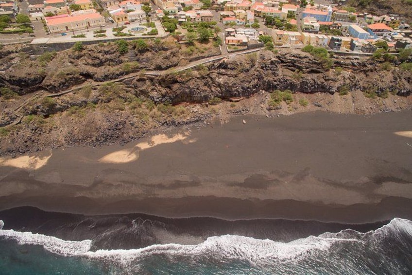 A coastal town with buildings, a beach, and waves crashing onto the shore. 3