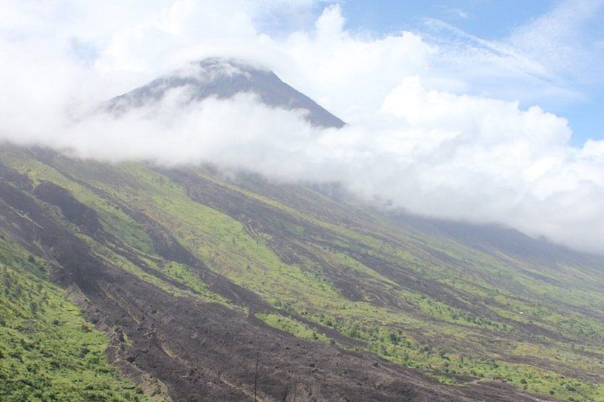 A mountain partially obscured by clouds, with green vegetation and rocky terrain. 1