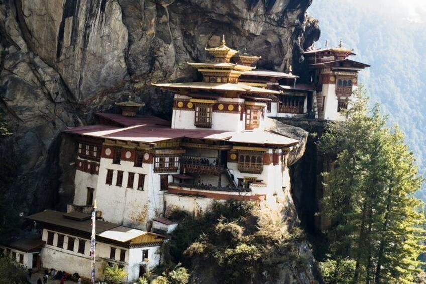 A multi-tiered monastery perched on a cliffside with a mountainous backdrop. 4