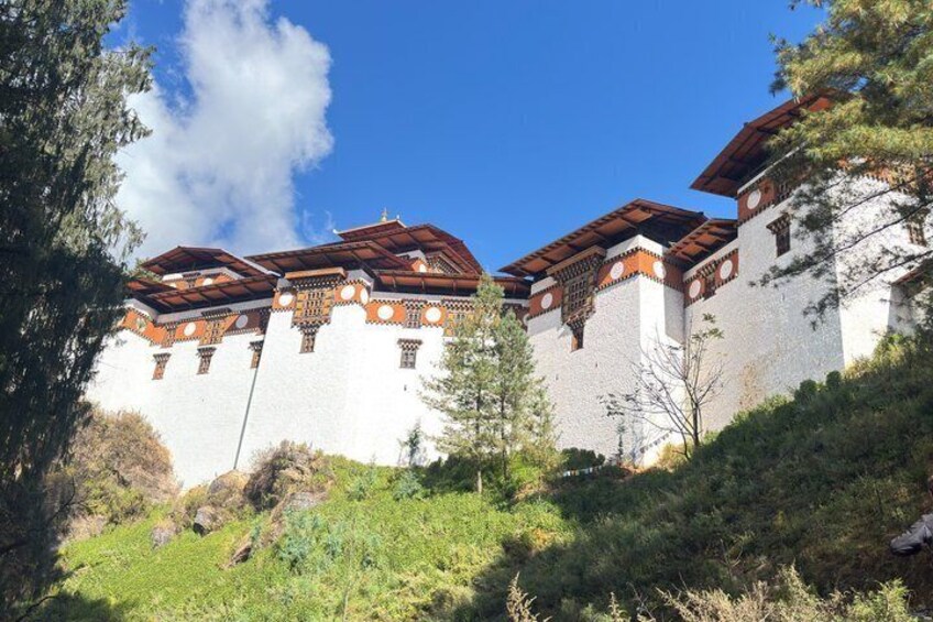 A traditional building with white walls and red-tiled roofs, surrounded by greenery and trees. 5