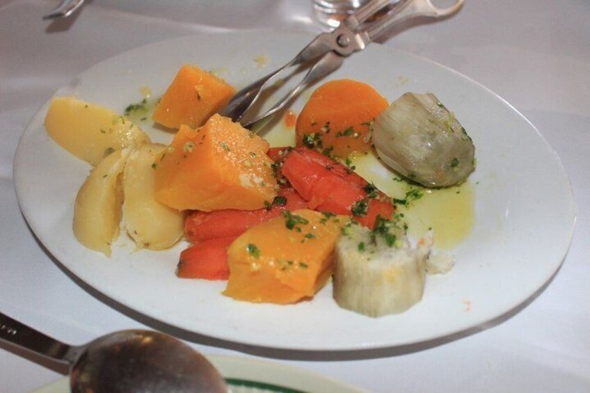 A plate of food with various vegetables and a piece of fish, garnished with herbs. 2