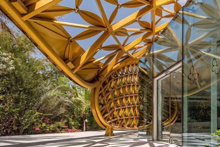 A modern architectural structure with a geometric design, surrounded by lush greenery and a glass facade. 3