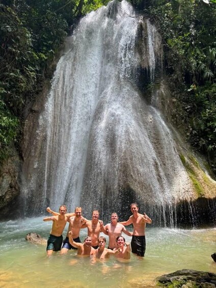 A group of people posing in front of a waterfall. 1