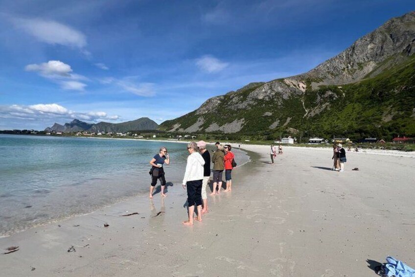 A beach with people walking along the shore, mountains in the background, and calm water. 4