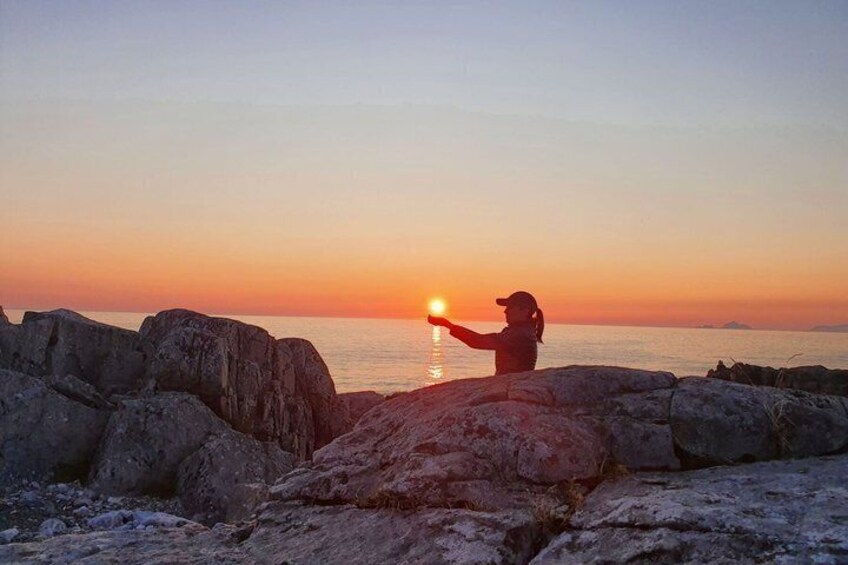 A person taking a photo of the sunset by the sea. 2