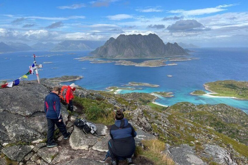 A mountainous landscape with hikers, a body of water, and a distant island. 3